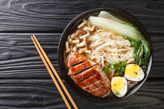 亚洲拉面汤与鸭，蘑菇，鸡蛋和白菜在碗中的黑桌关闭。从Abov的水平顶部视图