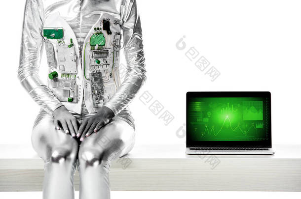 裁剪的图像机器人坐在桌子上靠近笔记本电脑与商业设备隔离在白色, 未来的技术概念