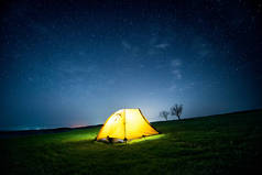 星光灿烂的天空下, 夜晚群山中闪耀的露营帐篷