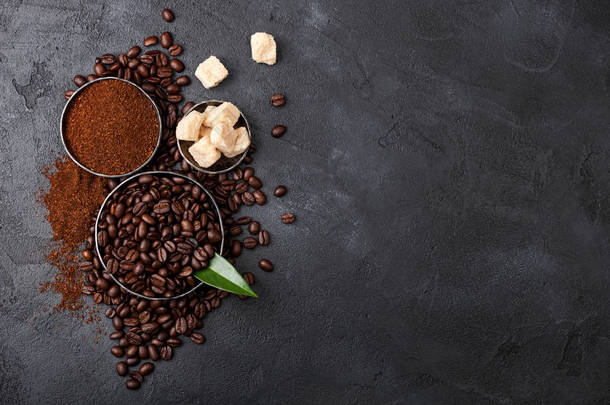 新鲜的生有机咖啡豆，带研磨粉和甘蔗糖块，黑色背景有咖啡树叶.