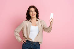 漂亮的黑发女人，带着粉色背景的智能手机自拍，体形呈阳性