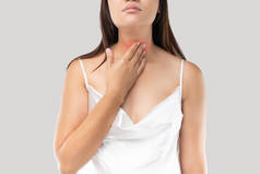 在灰色背景下,亚洲妇女喉头或甲状腺疼痛.酸倒流或心脏灼伤，颈部疼痛，人体问题概念