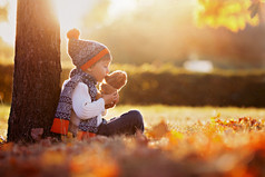 秋季的一天在公园内的玩具熊的可爱小男孩
