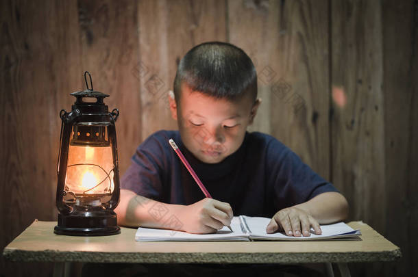贫困儿童写的书与油灯照明, 处境不利的孩子做作业, 教育概念.