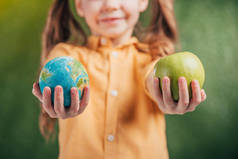 儿童持有地球模型的选择性焦点和模糊背景上的苹果, 地球日概念