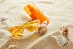 黄色时髦太阳镜，沙袋上有防晒霜和贝壳