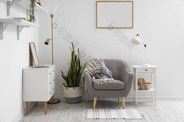 Interior of light living room with lamps, armchair and commode