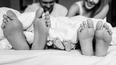 家庭与婴儿的腿的黑白图片在床上毯子在家里