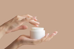 女人的手把手指伸进装有奶油的白色包装模型里。身体护理的概念，美容业