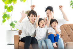 家长和两个男孩举手看电视的图片