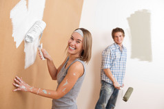 家居装修：年轻夫妇画墙与油漆滚筒