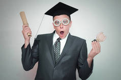 研究生在盖帽与文凭证书和金牌奖在手被隔绝在灰色背景。教育理念.