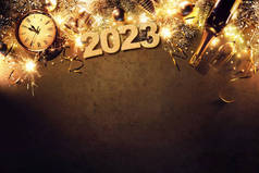 除夕2023年假日背景与冷杉树枝，时钟，圣诞球，香槟酒瓶，礼品盒和黑暗板上的灯
