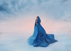 白雪公主穿着蓝色的雨衣, 在风中飘扬。一个在日出或日落背景下的旅行者, 一个被冰雪覆盖的冰冻山谷, 一个天堂与地球相遇的地方。