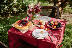 酒杯, 浆果馅饼和水果在餐桌上的花园