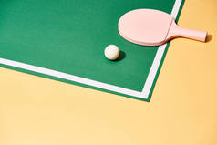 黄底桌上乒乓球的球拍和球拍