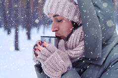 女人获取温暖由冬季的森林里喝杯茶