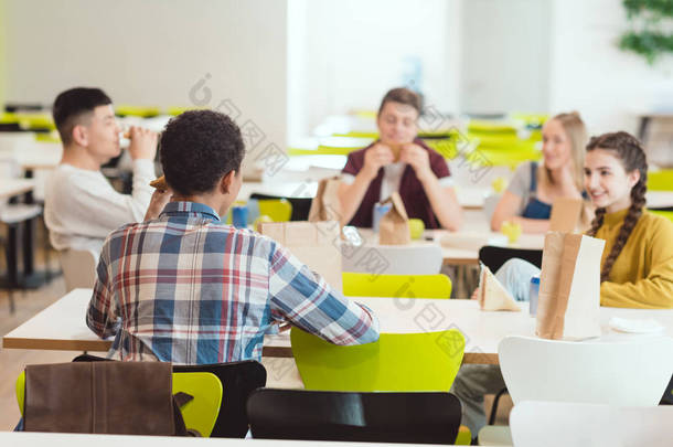一群十几岁的学生在学校食堂吃午餐时聊天