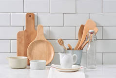 质朴的厨具和陶瓷水罐与木制炊具设置在白色瓷砖背景