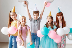 一群小孩子有生日聚会, 戴喜庆的帽子, 抱着气球, 一起开心, 玩游戏。小可爱的女孩庆祝她的生日, 邀请朋友, 有愉快的神色
