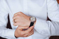 一个穿白衬衣的人正在戴上他的手表。新郎要去参加婚礼。商人为工作日做准备.