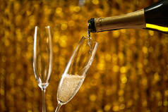 将香槟倒入玻璃金色时尚背景与金色散景圈的地方文本