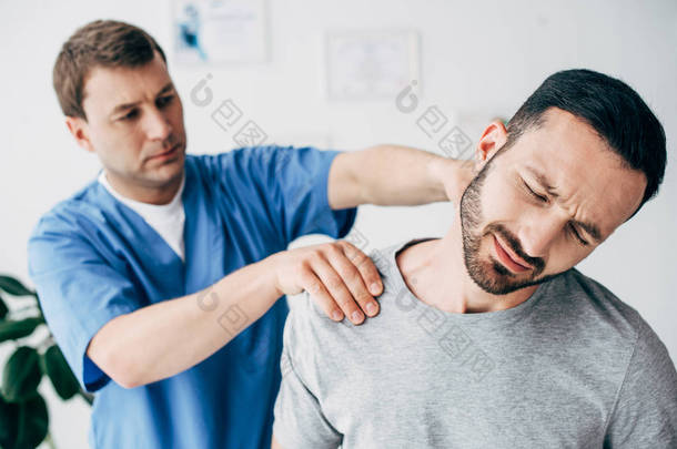 在诊所的按摩柜中,患者和医生按摩男人颈部的选择性焦点