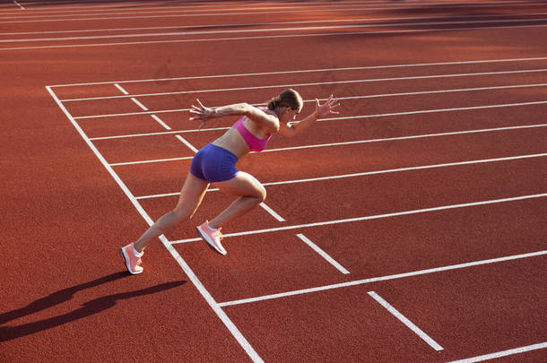 在起跑线上一名白人妇女，女运动员，在公共体育场、运动场或室外跑道进行跑步训练。夏季运动会.
