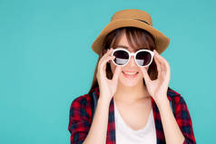 美丽的肖像画年轻的亚洲女人头戴帽子，戴着太阳镜，面带微笑，充满自信地享受在蓝色背景下度过的暑假之旅，旅游的亚洲女孩带着旅游的快乐.
