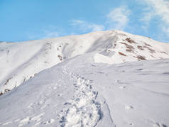 在蓝天的映衬下，在白雪覆盖的高山上做着详细的说明。小径上新雪中的脚步声