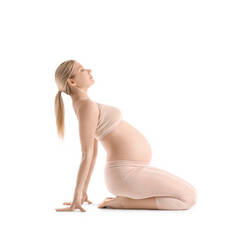 漂亮的年轻孕妇在白种人的背景下练习瑜伽