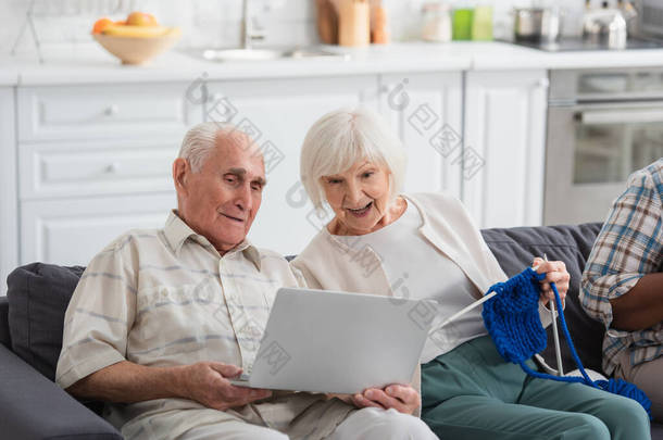 老人抱着手提电脑，带着纱线在养老院里与快乐的朋友<strong>亲近</strong>