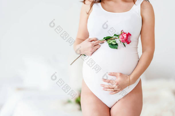 一个穿着白衣的孕妇手持美丽的花朵。可爱的概念健康怀孕，<strong>母亲节</strong>，<strong>母亲节</strong>的概念。带有复制空间的横幅.