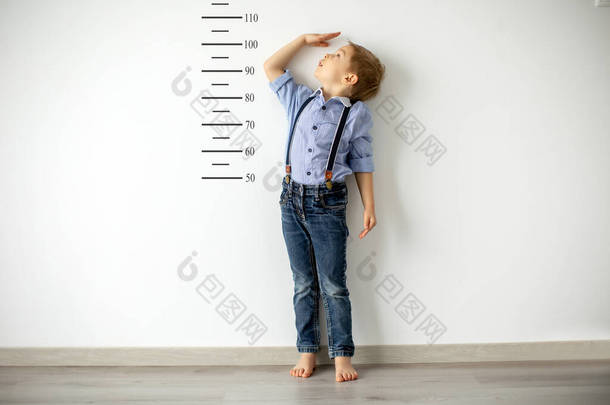 小孩子，金发碧眼的男孩，对照房间的墙壁测<strong>量身高</strong>