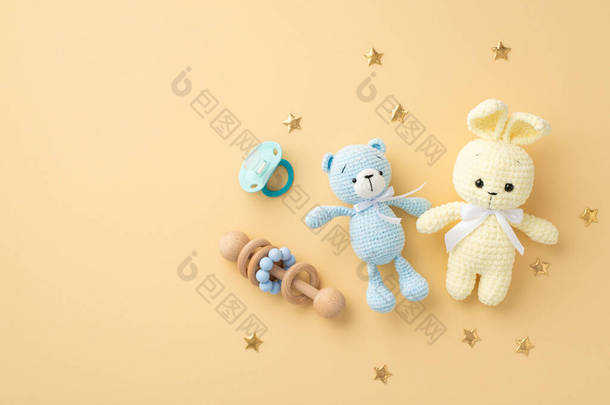 婴儿用品概念。针织兔子玩具、玩具玩具、木制响尾蛇、蓝色奶嘴、金色星辰的全景照片。