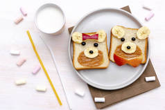 有趣的可爱的熊，狗脸三明治面包与花生酱，香蕉，苹果，牛奶，棉花糖。孩子们的甜甜点健康的早餐午餐食品艺术盘中，关门，尽收眼底.
