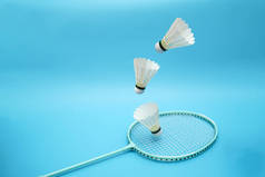 Badminton shuttlecocks and badminton racket on blue background