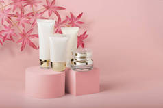 化妆品包装-产品架上的一组不同的化妆品空管的奶油和血清罐。漂亮，工作室拍摄。粉色背景的无名空白包件
