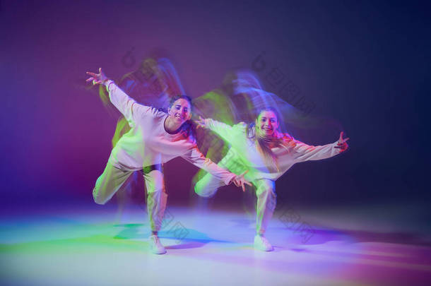 在霓虹灯下，年轻女孩在深蓝色紫色背景上跳嘻哈舞的肖像。Hobby 。运动概念、青年文化、积极的生活方式、行动、街头舞蹈