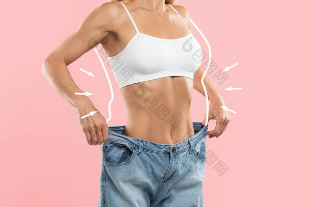 超大牛仔裤中无法辨认的瘦小女性与体重减轻后的比较、体侧有拉长脂肪轮廓的年轻瘦小女性与粉红背景的隔离、结合体