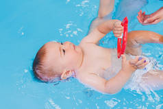 一个小男孩正在一个婴儿池里学习游泳。儿童的发展。儿童第一堂游泳课