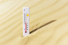 炎热的夏天在沙中的摄氏度级温度计.环境温度加8度