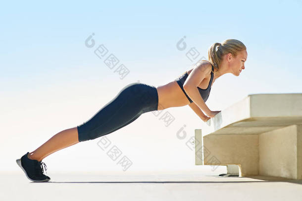 <strong>最大</strong>限度地锻炼这些核心肌肉。一个年轻女人在外面做俯卧撑的全长镜头