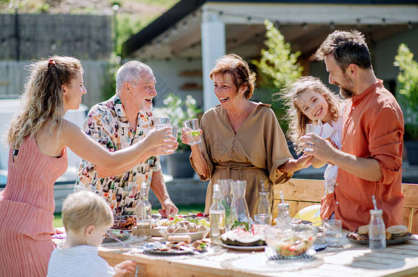 A multi generation family having garden <strong>party</strong> celebration, toasting and laughing.