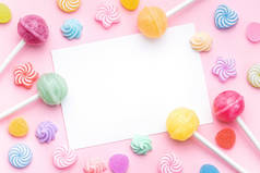 色彩艳丽的棒棒糖，粉色背景上的空白贺卡。平躺在地上，俯瞰四周