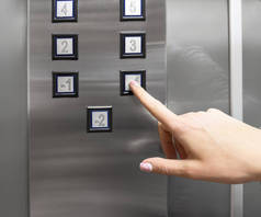 女性按下电梯按下按钮。手指头按电梯按钮.在办公室或公寓使用电梯的妇女