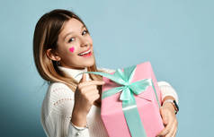 笑着的少女拿着一个大大的粉色礼品盒庆祝情人节，高兴地指着礼品盒