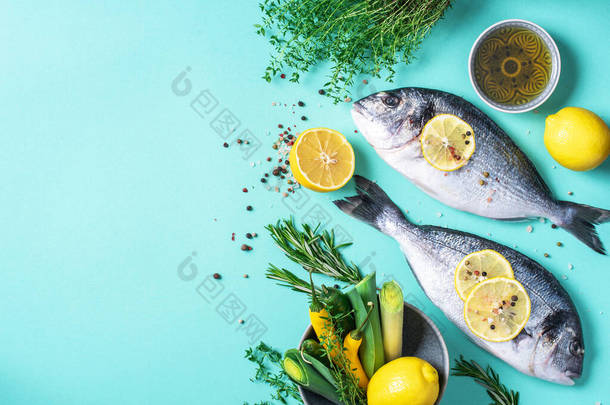 新鲜生海多头鱼柠檬片，香草，油，盐，胡椒，绿色蓝色背景。顶部视图。健康食品概念。复制空间。食品模式