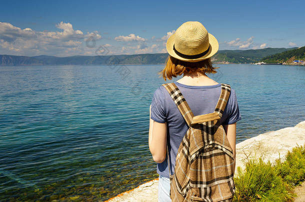 戴着帽子和背包的年轻女士欣赏 Listvyanka 村<strong>海滨</strong>的贝加尔湖<strong>夏日</strong>风光。