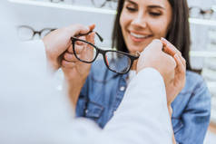男性眼科在光学中给女性眼镜的裁剪图像